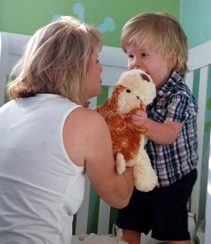 parent playing with child who is holding a stuffed animal