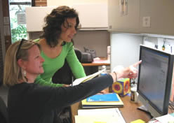two EI practitioners and administrators collaborating and looking at a computer